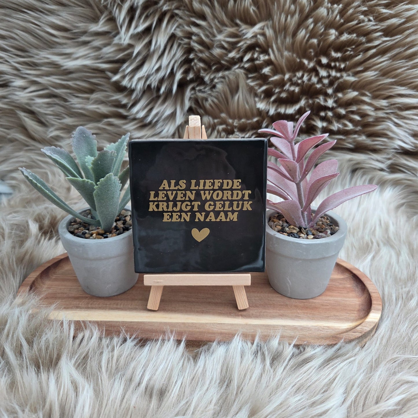Keramisch zwart tegeltje met gouden tekst “Als liefde leven wordt krijgt geluk een naam” op houten standaard met twee plantjes – decoratie of cadeau.